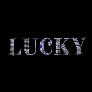 May include: The word "LUCKY" spelled out in rhinestones. Each letter is made up of small, iridescent rhinestones.