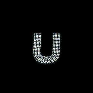 May include: The letter U is formed with small, clear rhinestones on a black background.