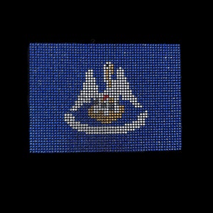 May include: A blue flag with a white ship and two white birds in the centre. The ship has a red sail and a yellow mast.