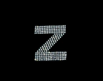 May include: The letter Z is formed using small, clear rhinestones on a black background.