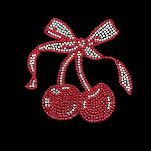 May include: A red and white rhinestone cherry design with a bow. The cherries are made of red rhinestones and the bow is made of white rhinestones.