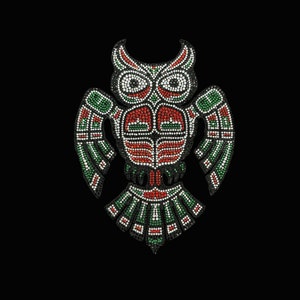 May include: A green, red, and black owl design made of rhinestones. The owl has large, round eyes and a detailed design on its wings and body.