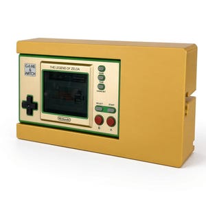 May include: A gold-coloured handheld electronic game console featuring a rectangular screen with the text The Legend of Zelda. The device includes a black directional pad, red A and B buttons, green select and start buttons, and a Game & Watch logo.