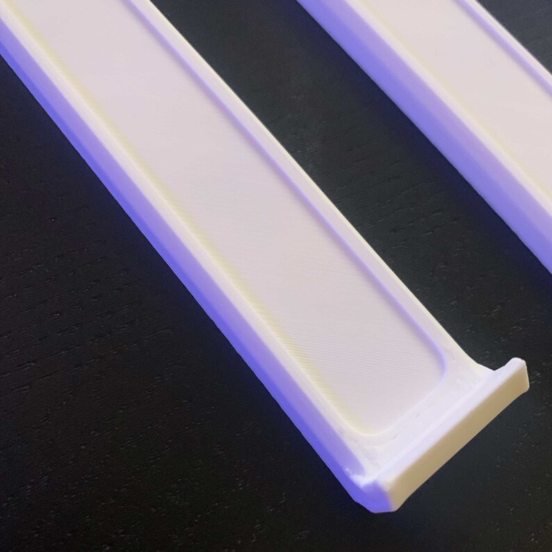 May include: Two white plastic shelf dividers, designed to fit into a shelf to create separate compartments. The dividers are angled to fit snugly into the shelf.