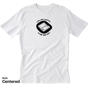 May include: White t-shirt with a black circle graphic featuring a Nintendo 3DS handheld gaming console and the text "I play with the 3D on".
