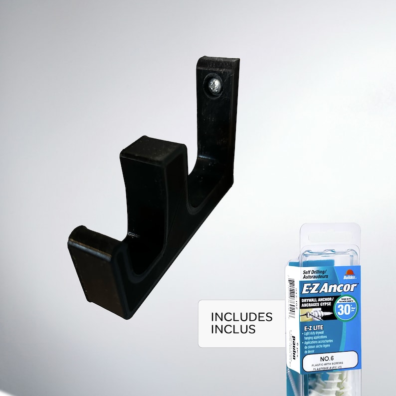 May include: Black plastic wall hook with two prongs. The hook is attached to a white wall. The package includes drywall anchors and screws. The package is labeled "E-Z Ancor" and "Includes/Inclus".