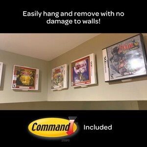 May include: Four Nintendo DS game cases are displayed on a wall using Command Strips. The cases are all for Zelda games, and the text "Command Strips" and "Included" are visible below the cases.