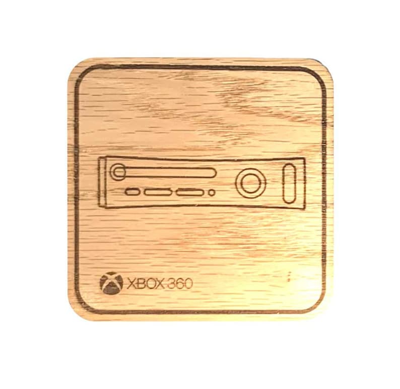 Op de afbeelding: Een houten onderzetter met een lasergegraveerd ontwerp van een Xbox 360-console. De onderzetter is bruin en heeft een vierkante vorm. De tekst "XBOX 360" is ook gegraveerd op de onderzetter.