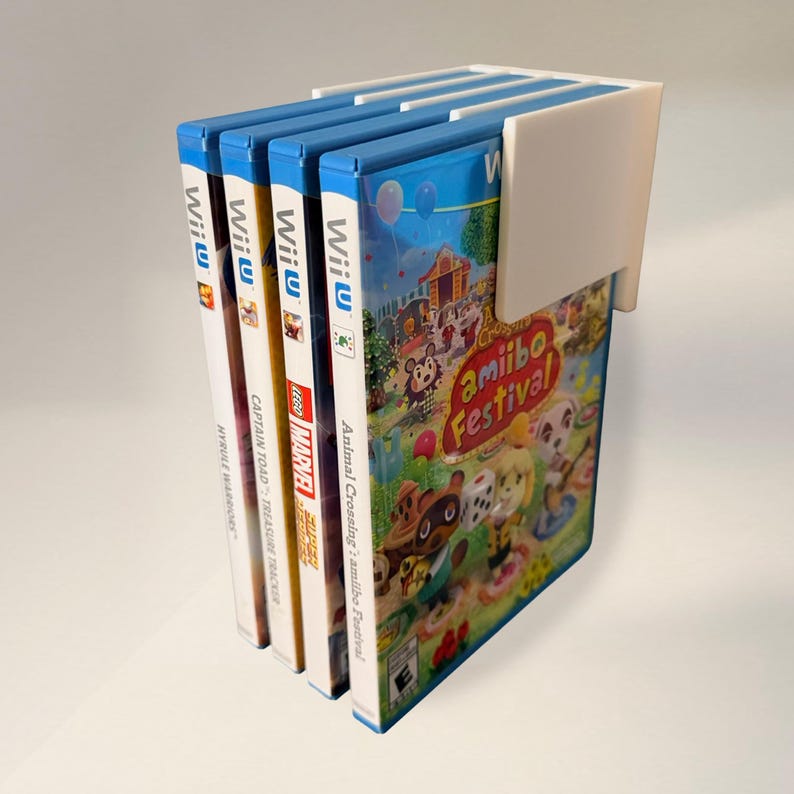 May include: A white plastic game holder with four Wii U game cases. The game cases have blue spines and colorful game art. The games include "Animal Crossing: amiibo Festival," "LEGO Marvel," and "Captain Toad: Treasure Tracker."