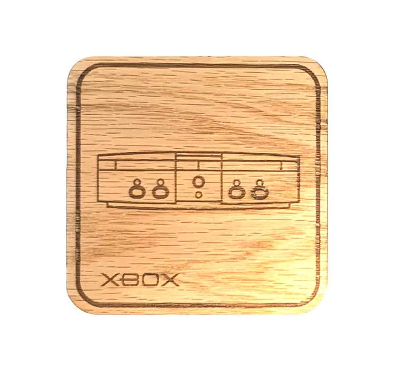 Op de afbeelding: Een houten onderzetter met een lasergegraveerd beeld van de originele Xbox-console. De onderzetter is lichtbruin en heeft een licht getextureerd oppervlak. De tekst "XBOX" is gegraveerd onder het consolebeeld.