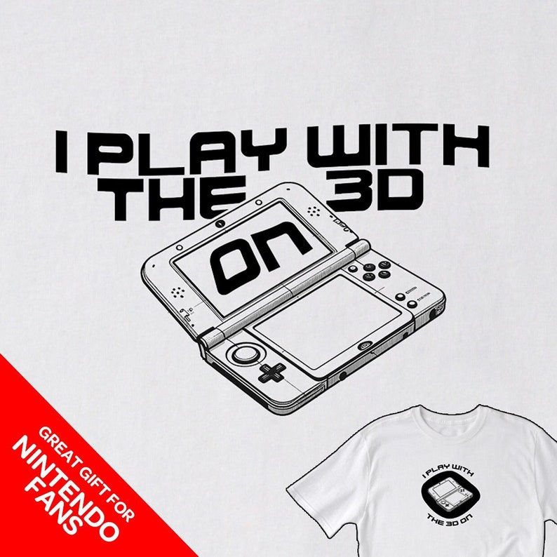 May include: A white t-shirt with a black and white illustration of a Nintendo 3DS handheld gaming console. The text "I Play With The 3D On" is printed above the console. The text "Great Gift For Nintendo Fans" is printed in the lower left corner of the image.