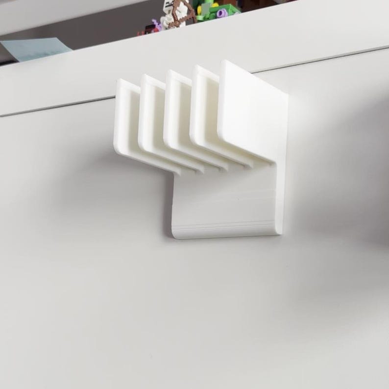 Puede incluir: Un organizador blanco montado en la pared con m&uacute;ltiples ranuras. El organizador est&aacute; hecho de un material s&oacute;lido y opaco y tiene un dise&ntilde;o limpio y moderno. Parece estar dise&ntilde;ado para guardar art&iacute;culos como correo o papeles peque&ntilde;os. El organizador est&aacute; montado en una pared blanca.