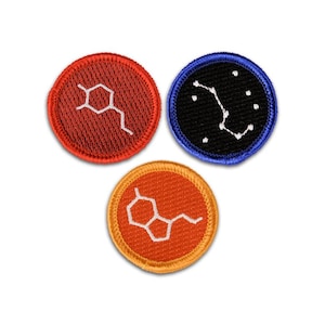 May include: Three circular embroidered patches. One is red with a white chemical structure, one is orange with a white chemical structure, and one is black with a blue border featuring a white star constellation pattern of connected dots.