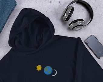 May include: A navy blue hooded sweatshirt with a small embroidered design of a yellow sun, a blue and green earth, and a white crescent moon.