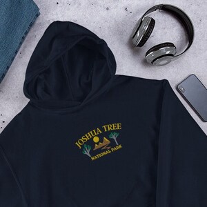 May include: A navy blue hooded sweatshirt with a yellow and green embroidered design that says "Joshua Tree National Park".