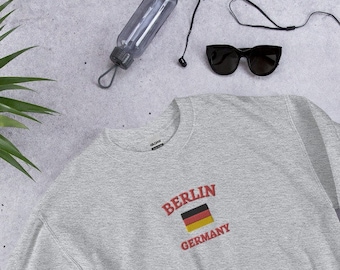 May include: A gray sweatshirt with a red embroidered design that says "BERLIN GERMANY" with a small German flag.