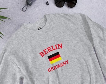 May include: Gray sweatshirt with a red print of "BERLIN GERMANY" and a small German flag.