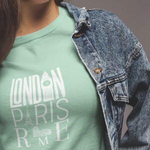 May include: A light green t-shirt with a white graphic design that says "LONDON PARIS ROME" with iconic landmarks from each city.