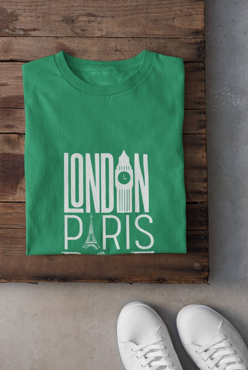 May include: A green t-shirt with the words "LONDON PARIS" printed in white. The graphic includes an illustration of Big Ben and the Eiffel Tower.