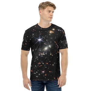 May include: A black t-shirt with a galaxy print featuring a bright white star and many smaller stars in shades of white, yellow, and orange.