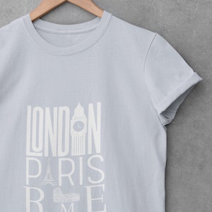 May include: A light blue t-shirt with a white graphic print of the words "LONDON PARIS ROME" with iconic landmarks from each city.