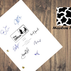 May include: A white sheet of paper featuring multiple blue signatures and a black and white "The Office" logo. The logo shows two stick figures and the show's title. The paper has gold eyelets and is set against a wooden background.