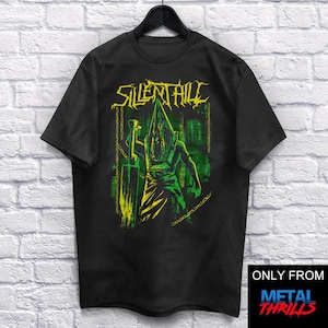 Pode incluir: Camiseta preta com um gráfico verde e amarelo de uma figura que usa uma cabeça em forma de pirâmide e segura uma faca grande. O texto "SILENT HILL" é impresso em amarelo acima da figura. O texto "ONLY FROM METAL THRILLS" é impresso em branco sobre fundo preto no canto inferior direito da camiseta.