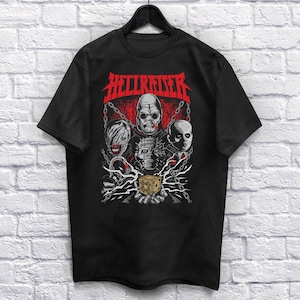 May include: Black t-shirt featuring a graphic of characters from the Hellraiser film franchise. The graphic depicts the characters holding a puzzle box with chains and a red background. The text "Hellraiser" is printed in white above the graphic.