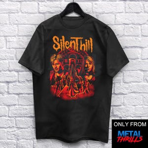 May include: Black t-shirt with a graphic print of characters from the video game Silent Hill. The graphic features the characters in front of a red and orange background with the text "Silent Hill" in orange.