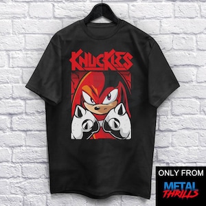 Puede incluir: Camiseta negra con un gráfico rojo y blanco de Knuckles de Sonic the Hedgehog. El gráfico presenta a Knuckles con los puños cerrados y el texto "Knuckles" en una fuente de banda de metal.