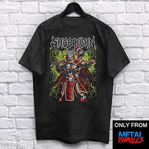 Puede incluir: Camiseta negra con un gráfico de un guerrero enmascarado, sosteniendo un arma. El diseño incluye el texto "SHAO KAHN" en una fuente estilizada, con un efecto de relámpagos verdes y amarillos. La camiseta es de Metal Thrills.