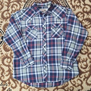 May include: A long-sleeved, button-down plaid shirt in shades of blue, red, and grey. The shirt features two chest pockets and a collared neckline. The brand name "EARLINES" is visible on the collar.