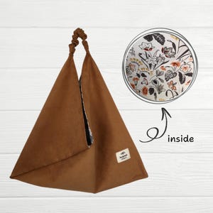 May include: A brown triangular tote bag with a floral print lining. The bag has a top handle and a label that says "Handmade Craft".
