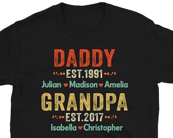 Könnte beinhalten: Schwarzes T-Shirt mit den Worten "DADDY EST.1991" in Orange und "GRANDPA EST.2017" in Gelb. Die Namen Julian, Madison, Amelia, Isabella und Christopher sind unter den Titeln aufgeführt. Das Shirt hat einen Vintage-Look.