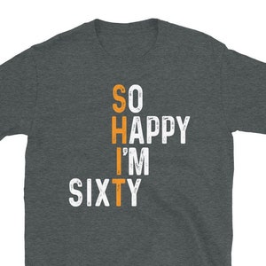 Peut inclure: T-shirt gris fonc&eacute; chin&eacute; avec un texte blanc qui dit "SO HAPPY I'M SIXTY" avec le mot "SIXTY" en orange.