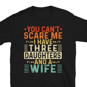 Könnte beinhalten: Schwarzes T-Shirt mit einem Vintage-Grafikdruck, auf dem "You can't scare me I have three daughters and a wife" steht.