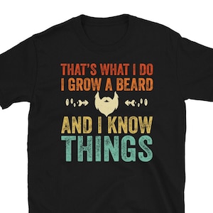Puede incluir: Camiseta negra con un gráfico de estilo vintage que dice "That's what I do I grow a beard and I know things". El gráfico presenta una barba con bigote y un esquema de color retro.