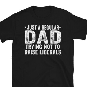 Może przedstawiać: Czarny T-shirt z białym tekstem, który brzmi "*Just a Regular* Dad Trying Not To Raise Liberals".
