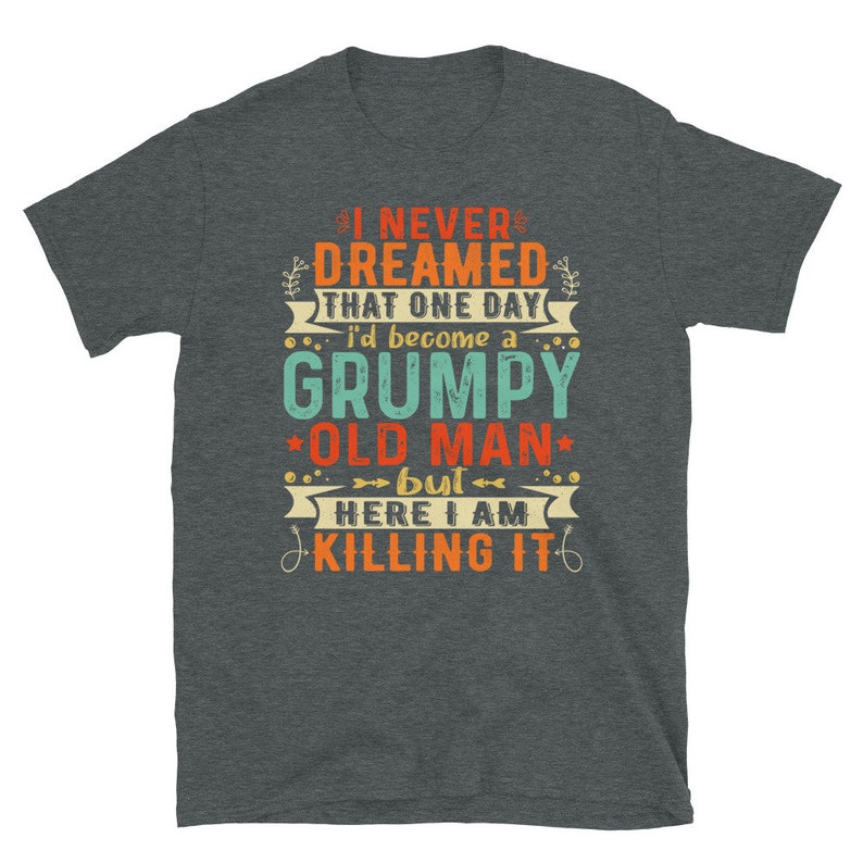 May include: A dark heather grey t-shirt with a vintage-style graphic that reads "I never dreamed that one day I'd become a grumpy old man, but here I am killing it".