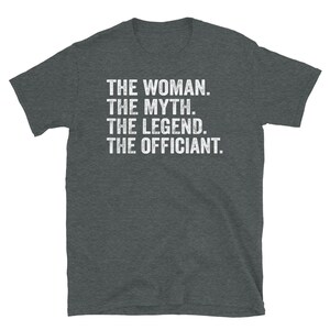 Puede incluir: Camiseta gris oscuro con texto blanco. El texto dice: "THE WOMAN. THE MYTH. THE LEGEND. THE OFFICIANT." La camiseta est&aacute; hecha de un material suave y tiene mangas cortas.