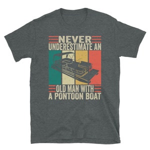 May include: A dark gray t-shirt with a vintage-style graphic that says "Never underestimate an old man with a pontoon boat". The graphic features a pontoon boat with a red, white, and blue color scheme.