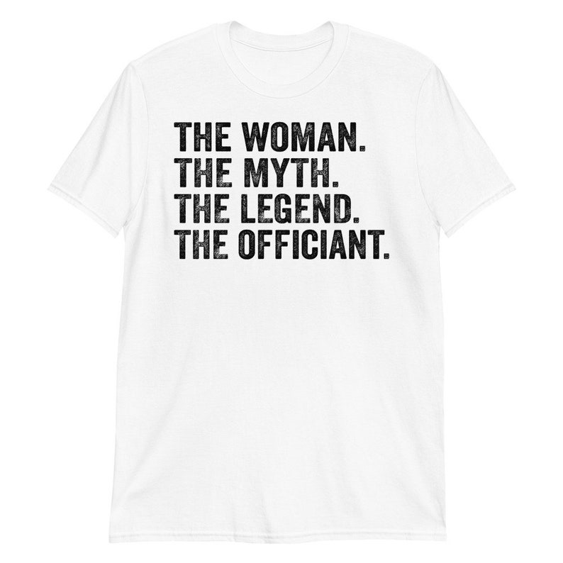 Puede incluir: Camiseta blanca con la frase "THE WOMAN. THE MYTH. THE LEGEND. THE OFFICIANT." en negro. El texto est&aacute; en una fuente desgastada. La camiseta tiene mangas cortas y cuello redondo.