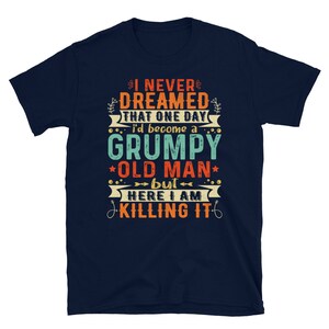 May include: Navy blue t-shirt with a vintage-style graphic that reads "I never dreamed that one day I'd become a grumpy old man, but here I am killing it".