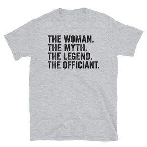 Puede incluir: Camiseta gris claro con el texto "THE WOMAN. THE MYTH. THE LEGEND. THE OFFICIANT." en negro con un dise&ntilde;o desgastado. La camiseta tiene mangas cortas y cuello redondo.