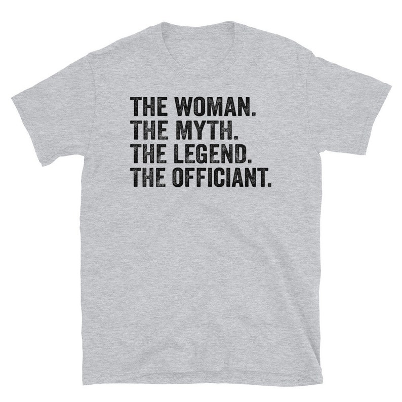 Puede incluir: Camiseta gris claro con el texto "THE WOMAN. THE MYTH. THE LEGEND. THE OFFICIANT." en negro con un dise&ntilde;o desgastado. La camiseta tiene mangas cortas y cuello redondo.