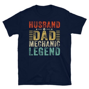 May include: Navy blue t-shirt with a vintage-style graphic that reads "Husband Dad Mechanic Legend".