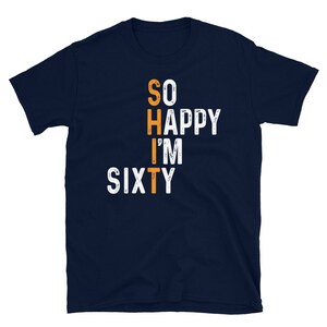 Peut inclure: T-shirt bleu marine avec un texte blanc qui dit "So Happy I'm Sixty". Le texte est dans un style de police d&eacute;form&eacute;. Le "I'm" est en orange.