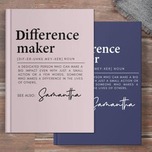 May include: Two pink and blue hardcover books with the word "Difference Maker" and its definition. The definition is "A dedicated person who can make a big impact even with just a small action or a few words. Someone who makes a difference in the lives of others." The word "Samantha" is written in cursive below the definition.
