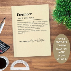May include: A beige journal with the definition of "Engineer" printed on the cover. The text includes a humorous description and the name "Alan Watson." A calculator, pencil, and coffee cup are visible.