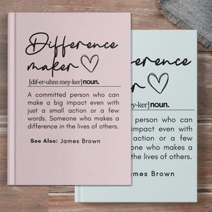 May include: Two pink and blue notebooks with the word "Difference Maker" and a heart on the cover. The definition of the word is written below the title. The definition reads: "A committed person who can make a big impact even with just a small action or a few words. Someone who makes a difference in the lives of others. See Also: James Brown"